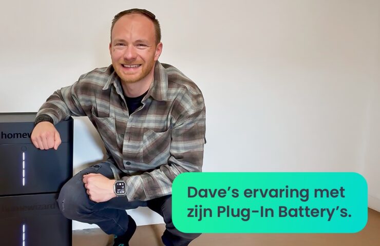 Blije man die zijn arm rust op twee thuisbatterijen van HomeWizard.